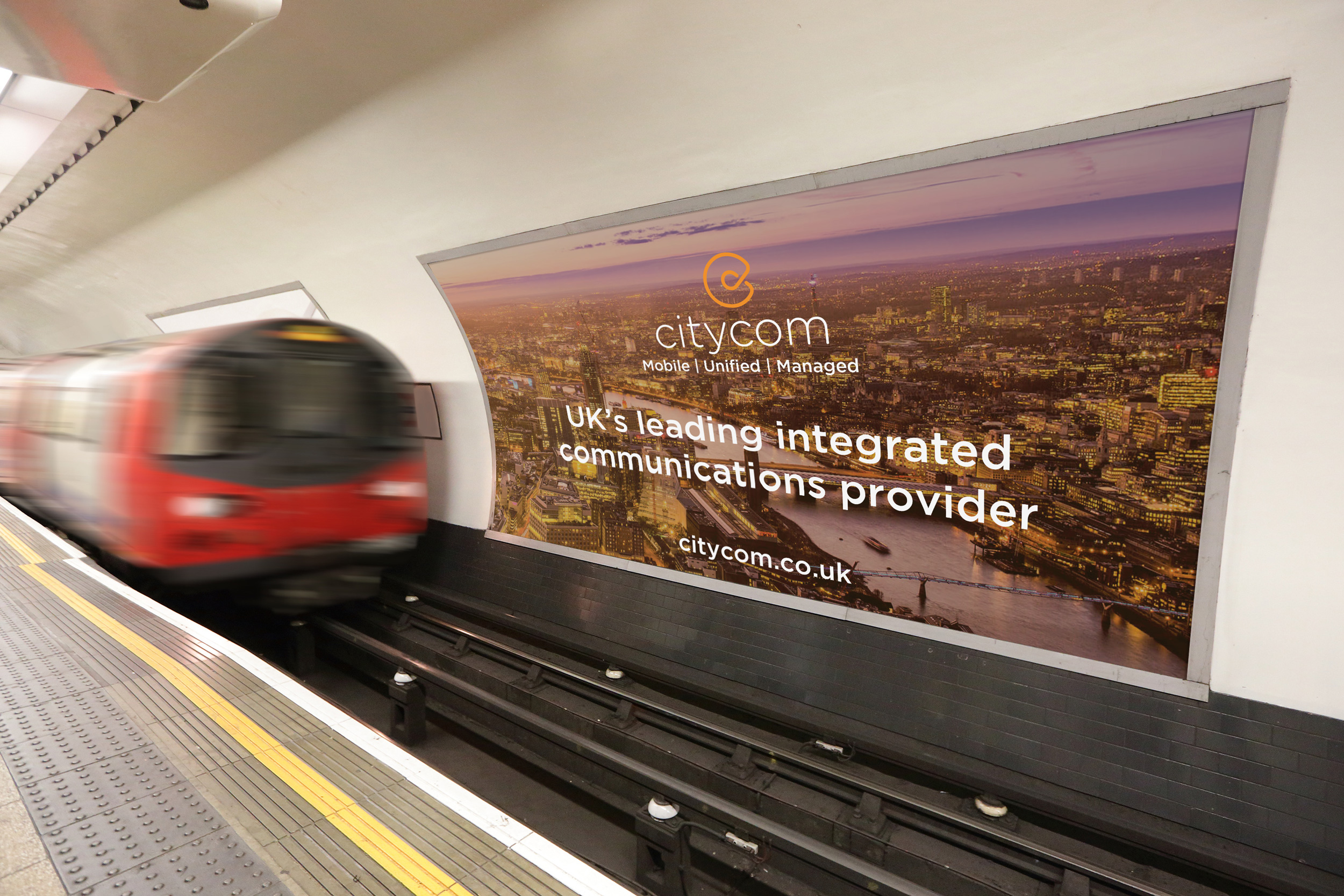Citycom advert on a billboard at a London Underground platform as a tube train pulls in